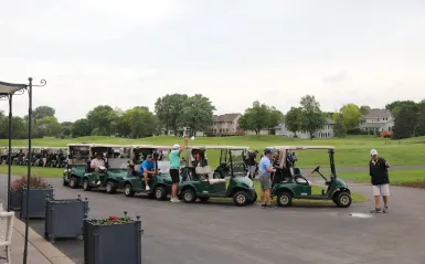 several golf carts lined up outside with people sitting in them