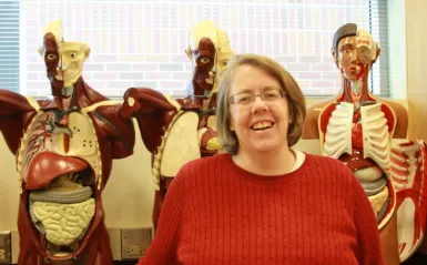 faculty member Dr. Tinna Ross standing in front of 3 anatomy models