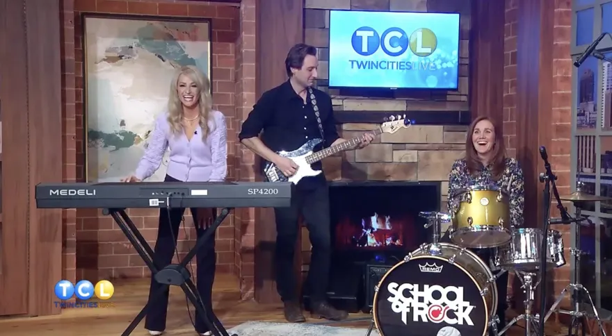 a photo of Adam Bart on Twin Cities Live playing music instruments with the hosts 
