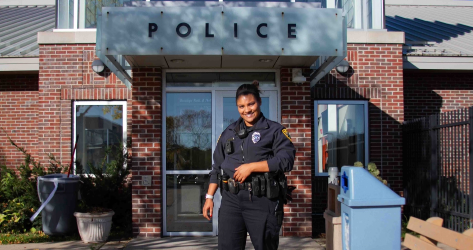 female alumni cop standing outside police station