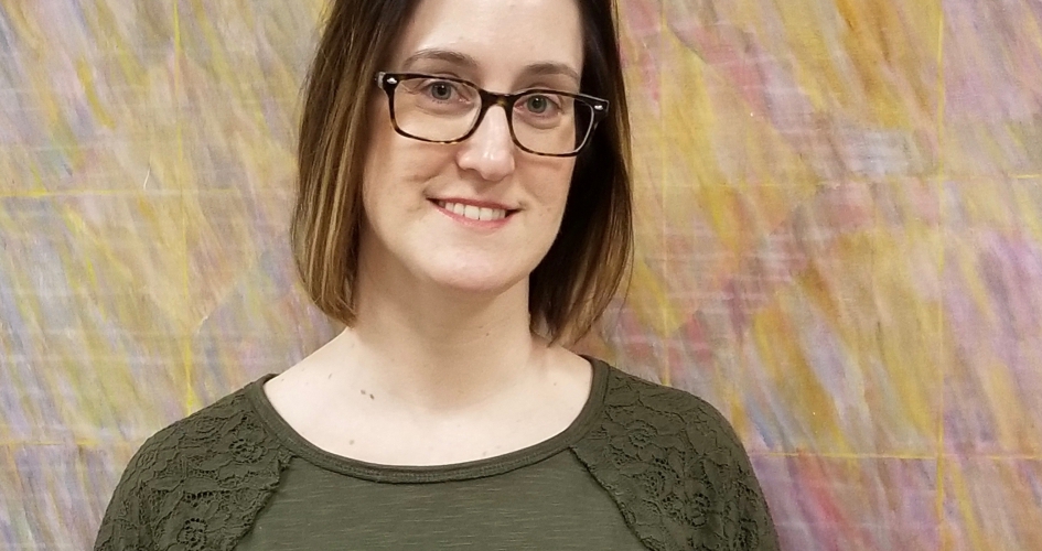 female student standing in front of a colorful piece of art