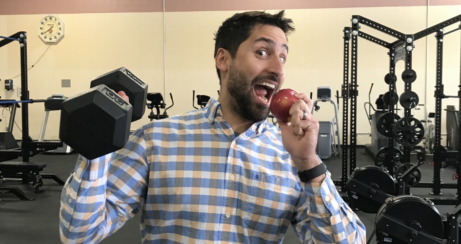 faculty member lifting a weight and eating an apple