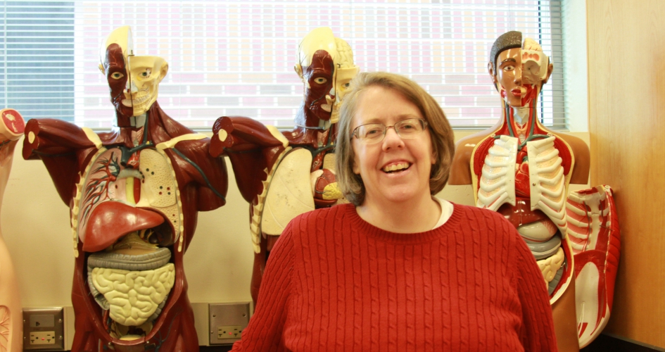 faculty member Dr. Tinna Ross standing in front of 3 anatomy models