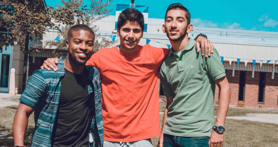 three male students smiling outside