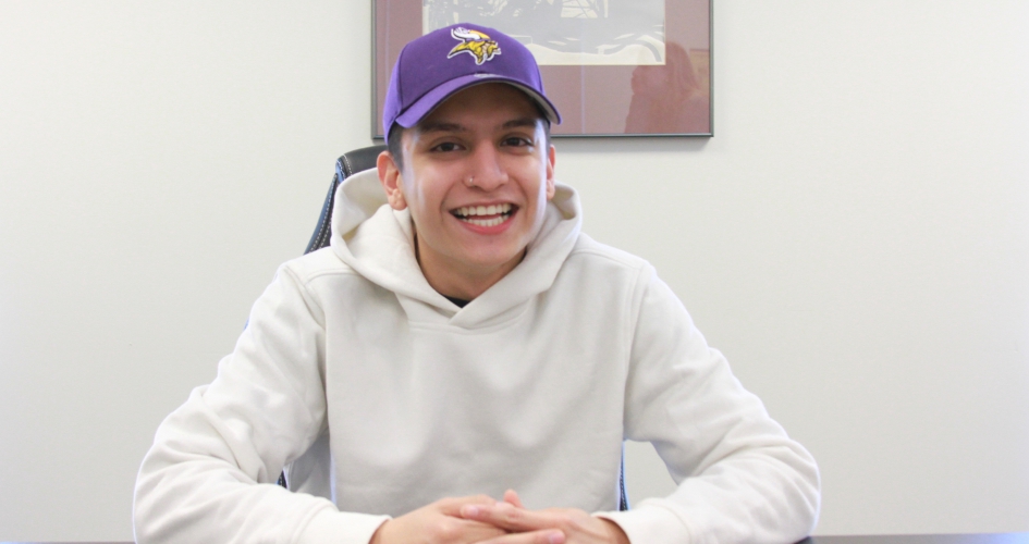 student Armando Morales sitting at a table smiling