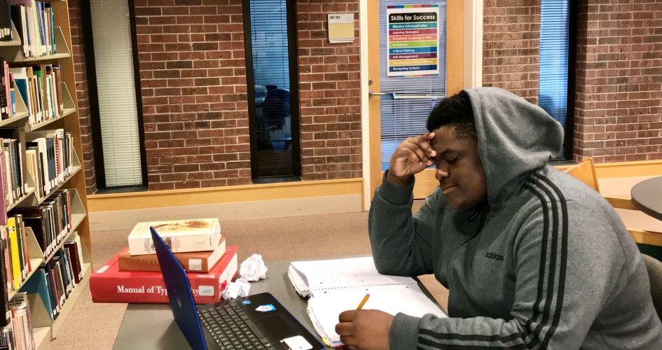 student stressfully doing their homework in the NHCC library