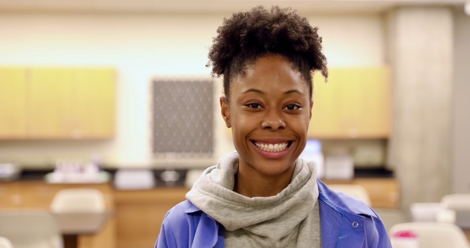 Phlebotomy student Tiahna James standing inside NHCC classroom smiling and facing the camera