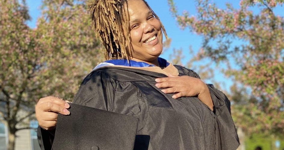 student to faculty member Audua Pugh in her graduation gown in the NHCC courtyard