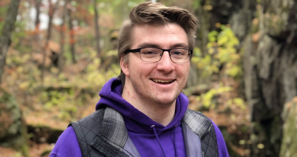 student Josh Betterman standing outside in a forest smiling for the camera
