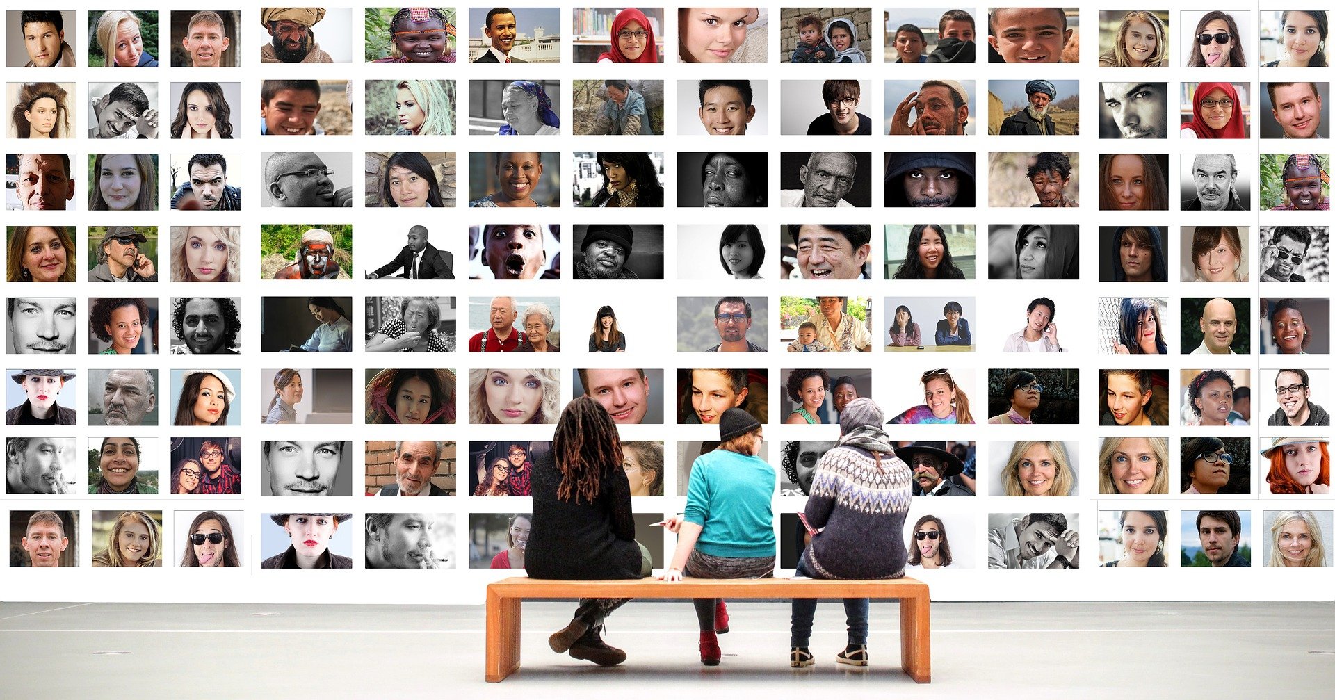 Image of students on a bench looking at photos on a wall.
