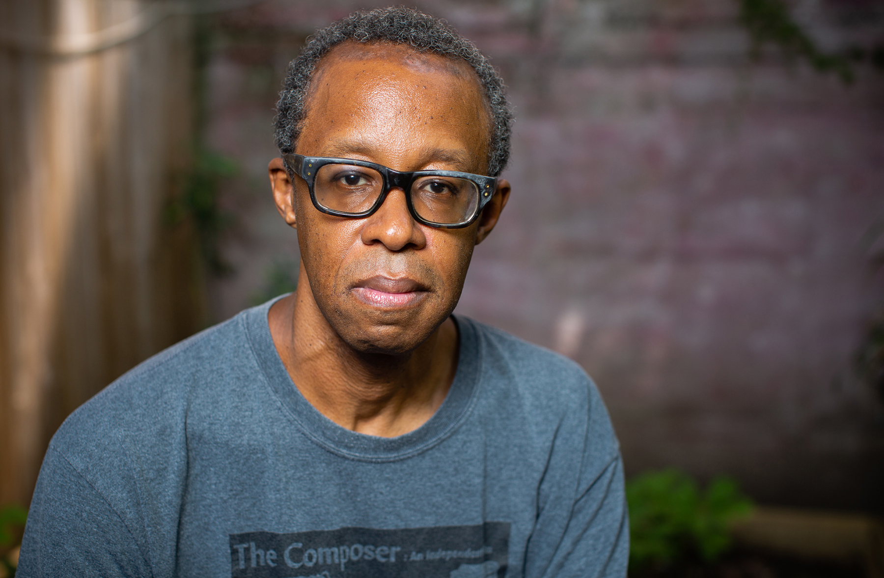 man wearing glasses with a brick background