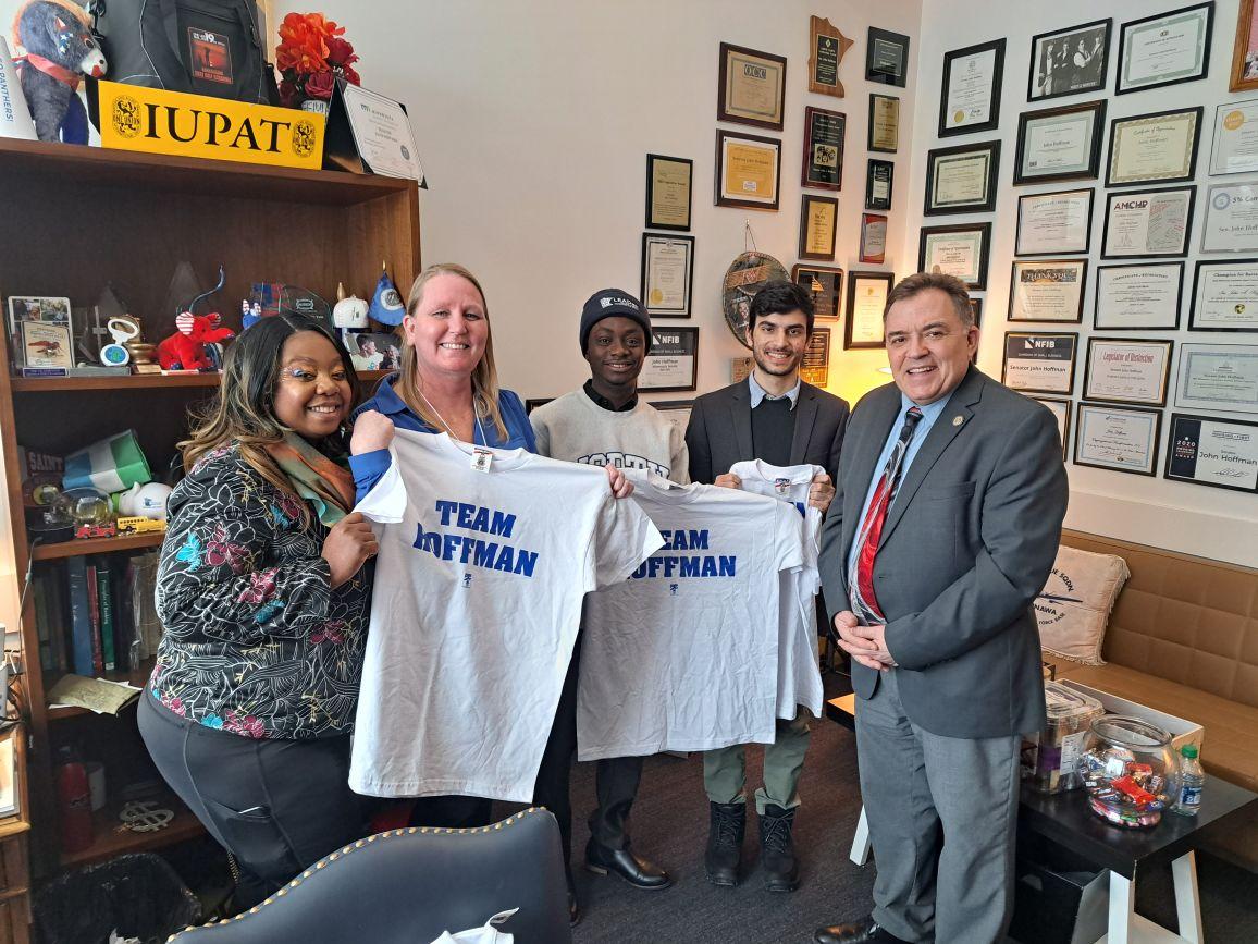 students holding t-shirts in a senator's office