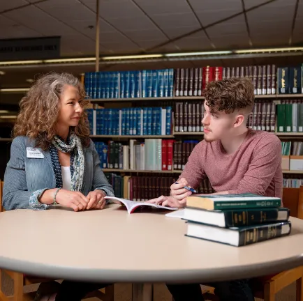 student sitting at a table talking with an advisor 