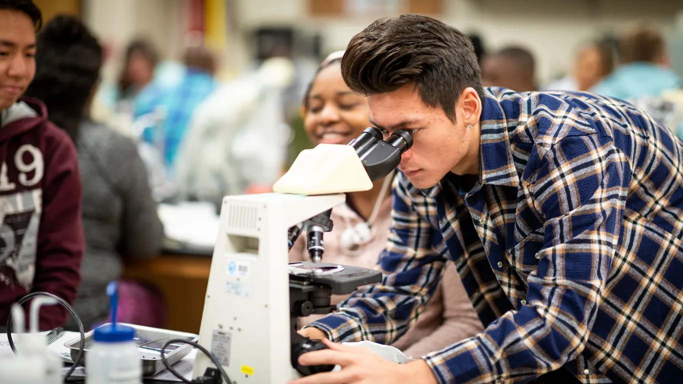 Biology class student looking at microscope 