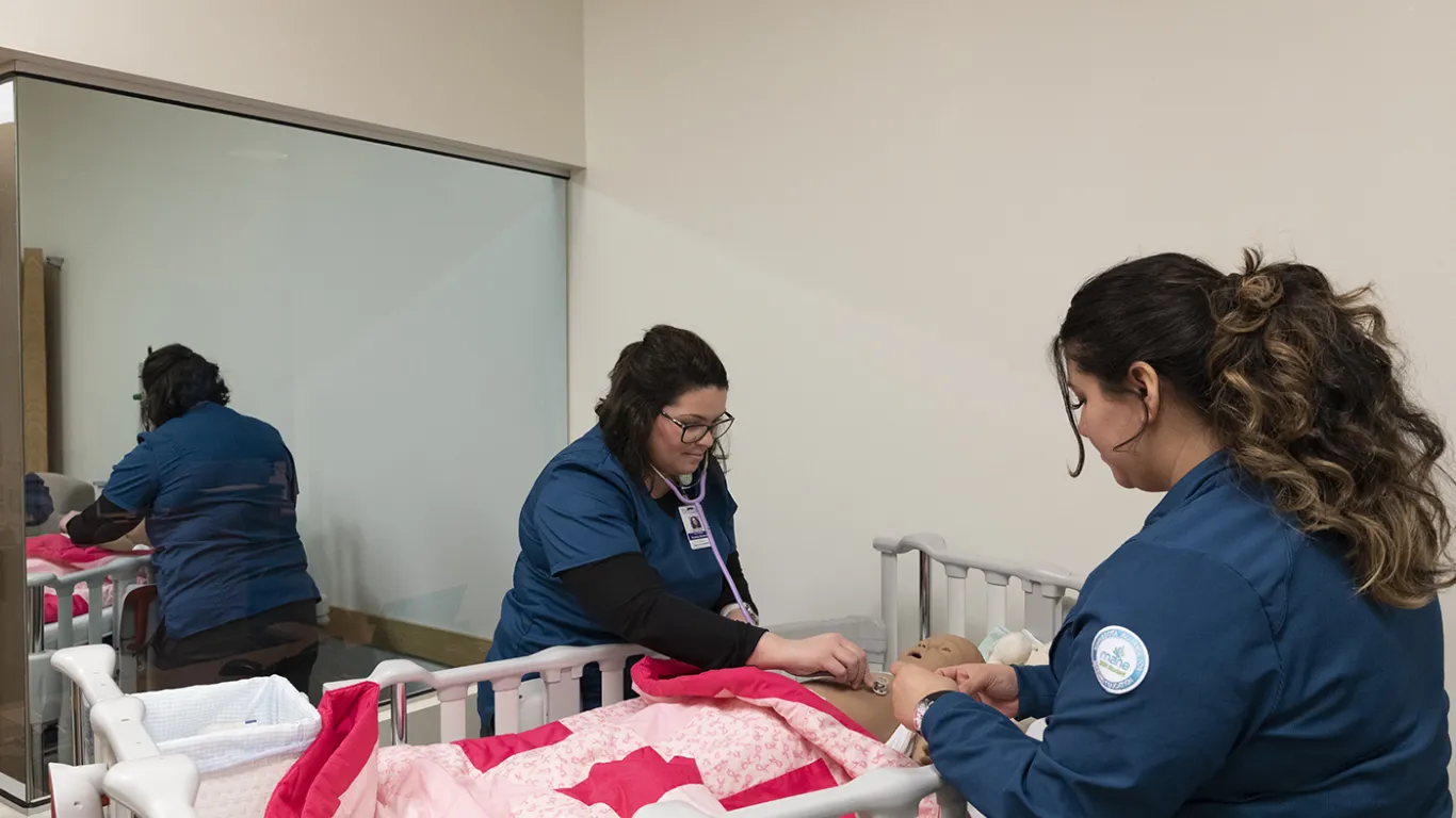 students working in a nursing lab over a bed