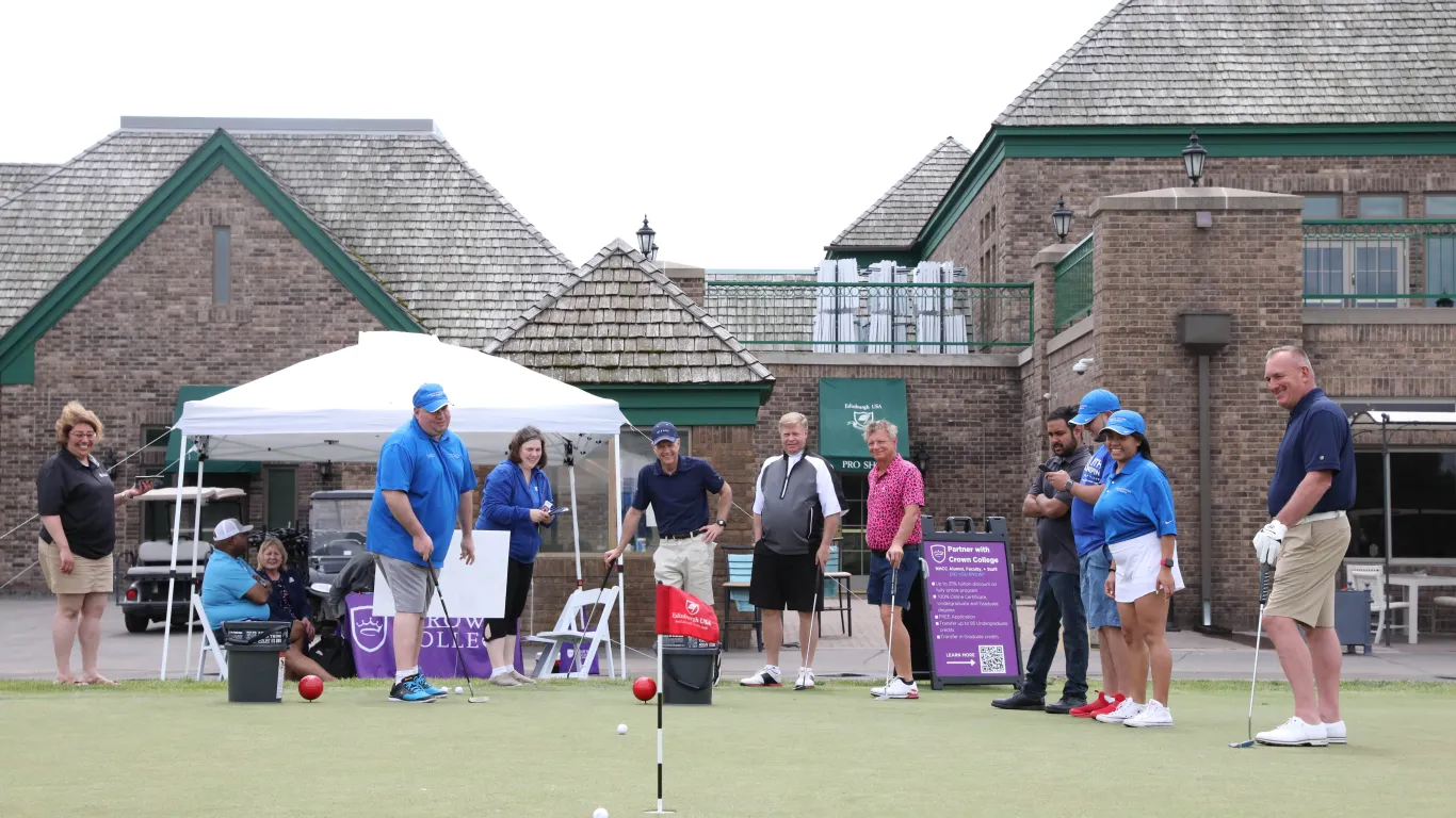 several people watching another put a golf ball into a hole