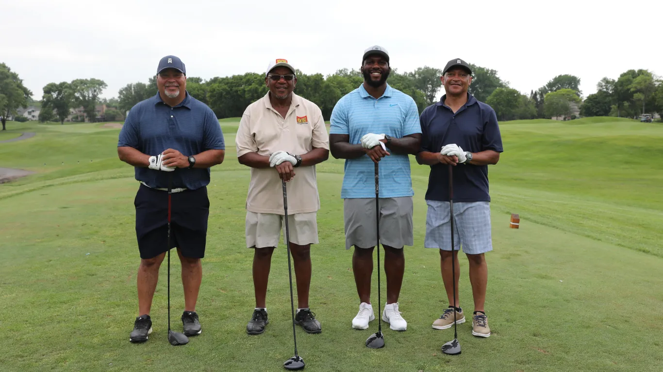 4 men grouped together for a phone on a golf course 