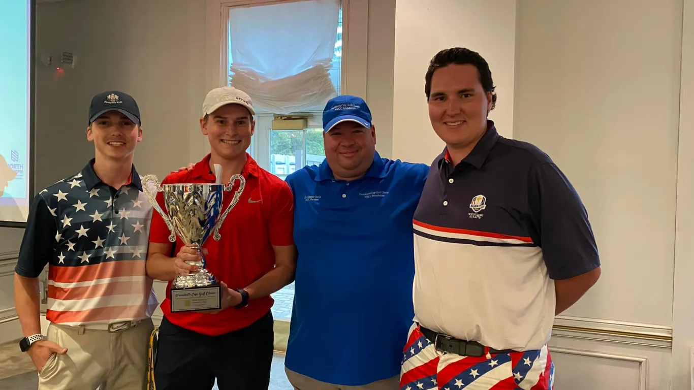 4 men grouped together for group photo, one holds a trophy cup