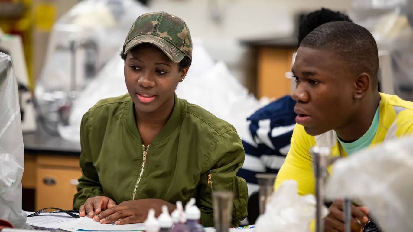 two students talking near lab equipment 