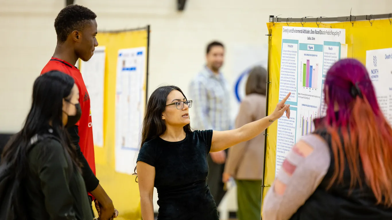 a student presenting research at a poster board 