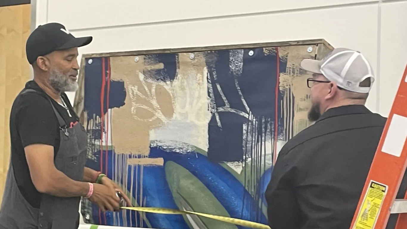 two people hanging a mural on campus