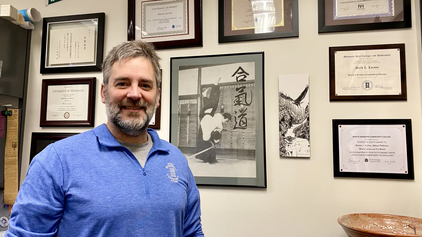 man smiling with plaques on the wall behind him 