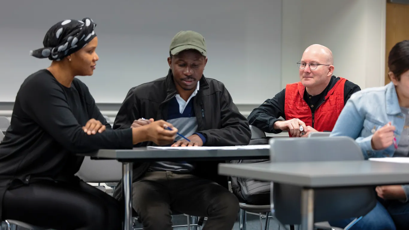 two students talking with an instructor listening