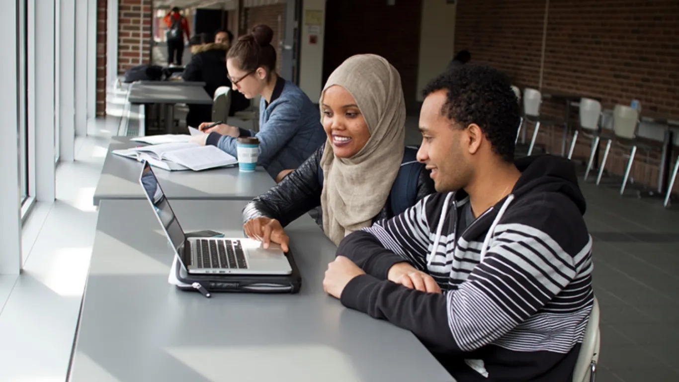 two students looking at a laptop 