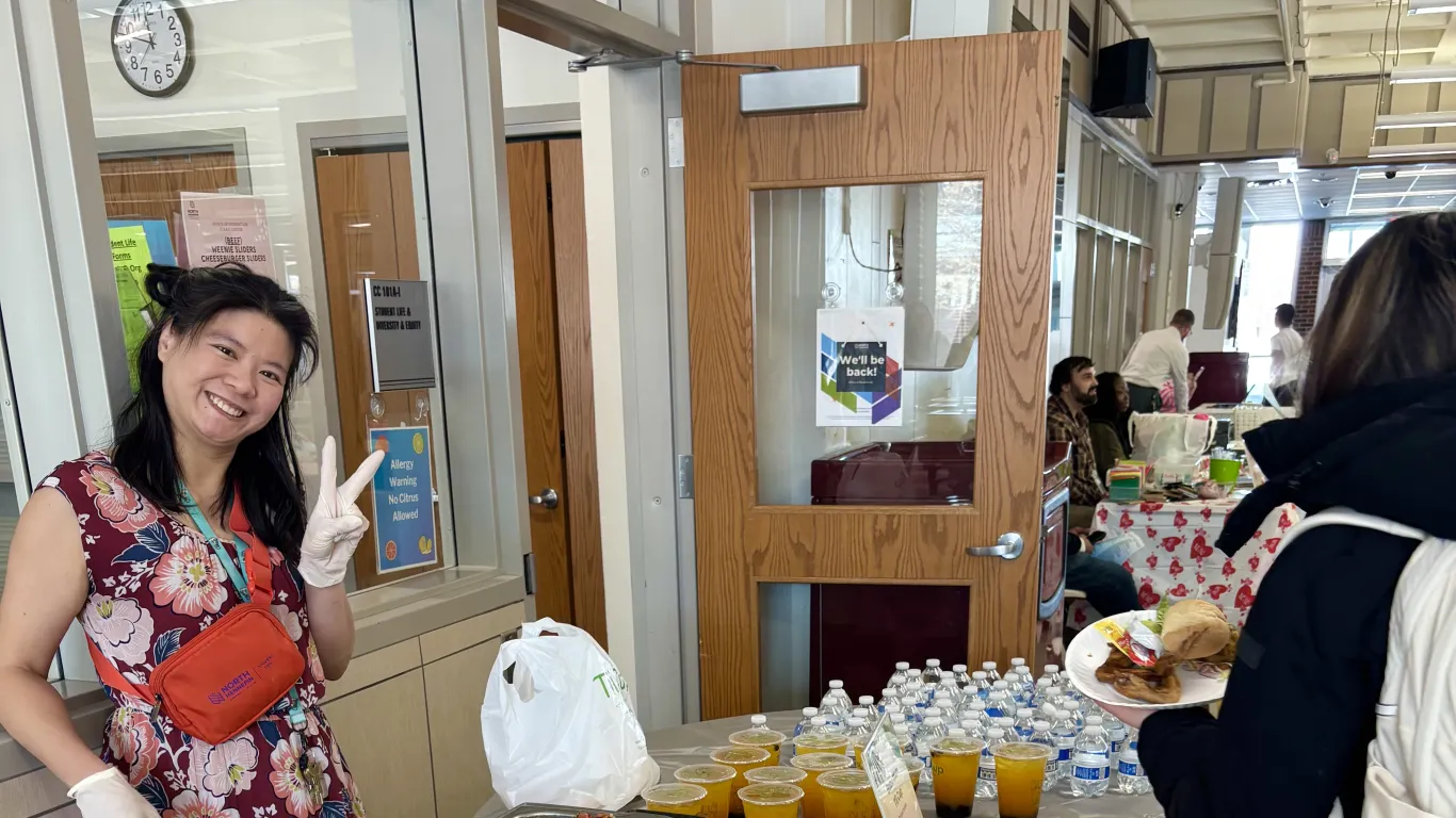 a photo of NHCC staff member, Hanh Le serving a student food at a Campus Center event. 