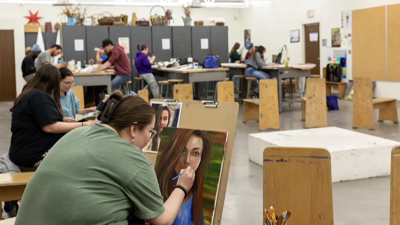 student painting with students in the background