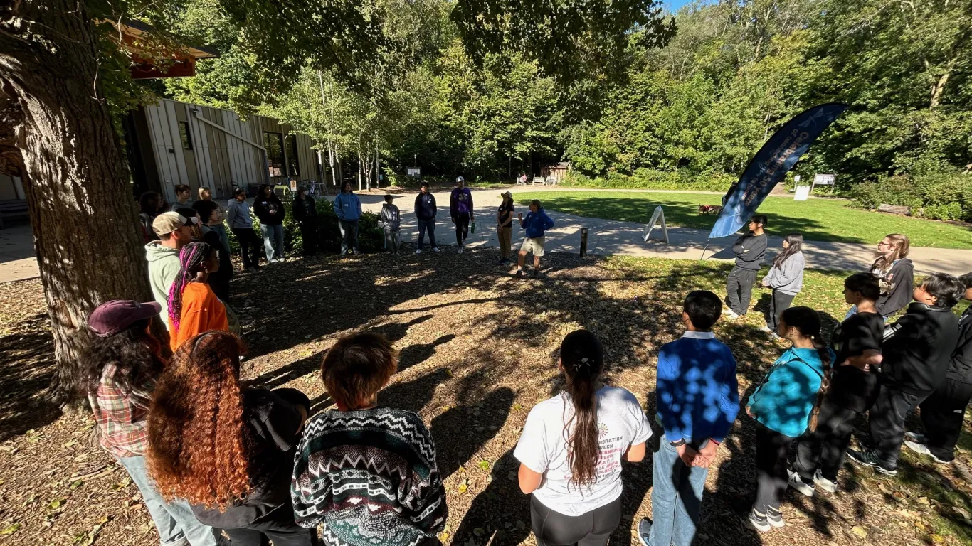 students standing outside in a large circle with an instructor