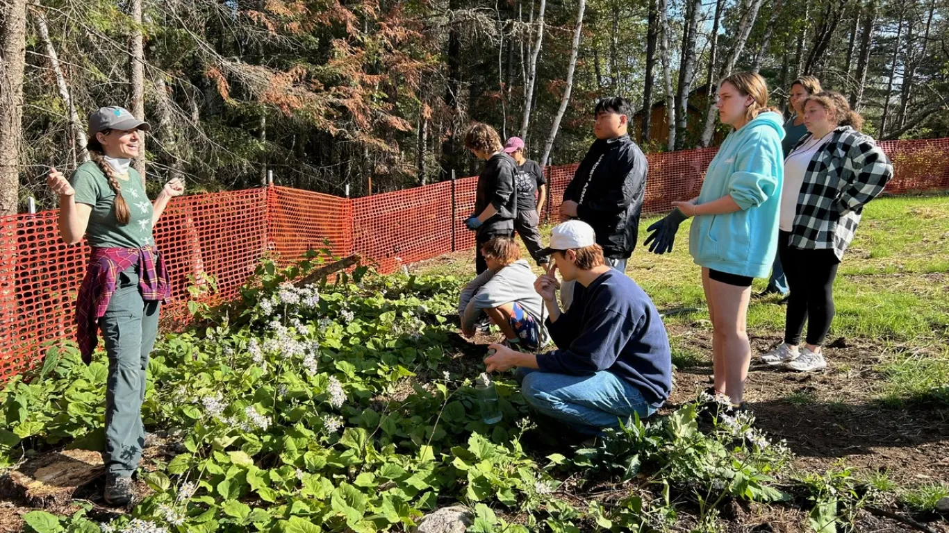 student standing in a garden while an instructor is talking