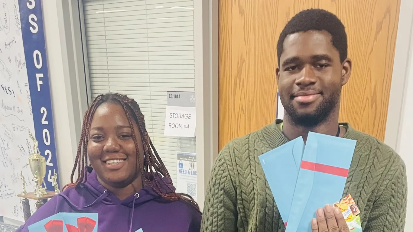 two students standing together holding up gift cards 