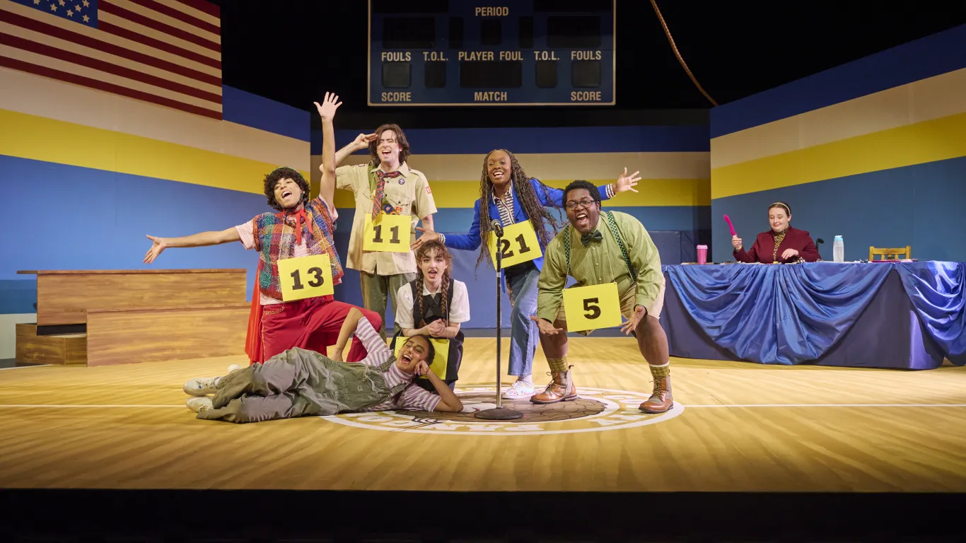 Actors performing on stage in the musical “The 25th Annual Putnam County Spelling Bee”