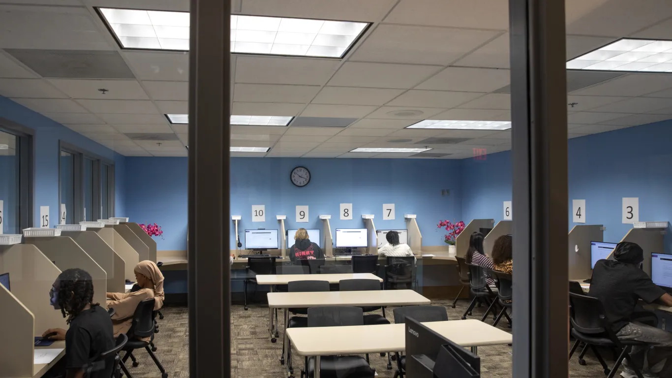 students sitting at small tables with computers