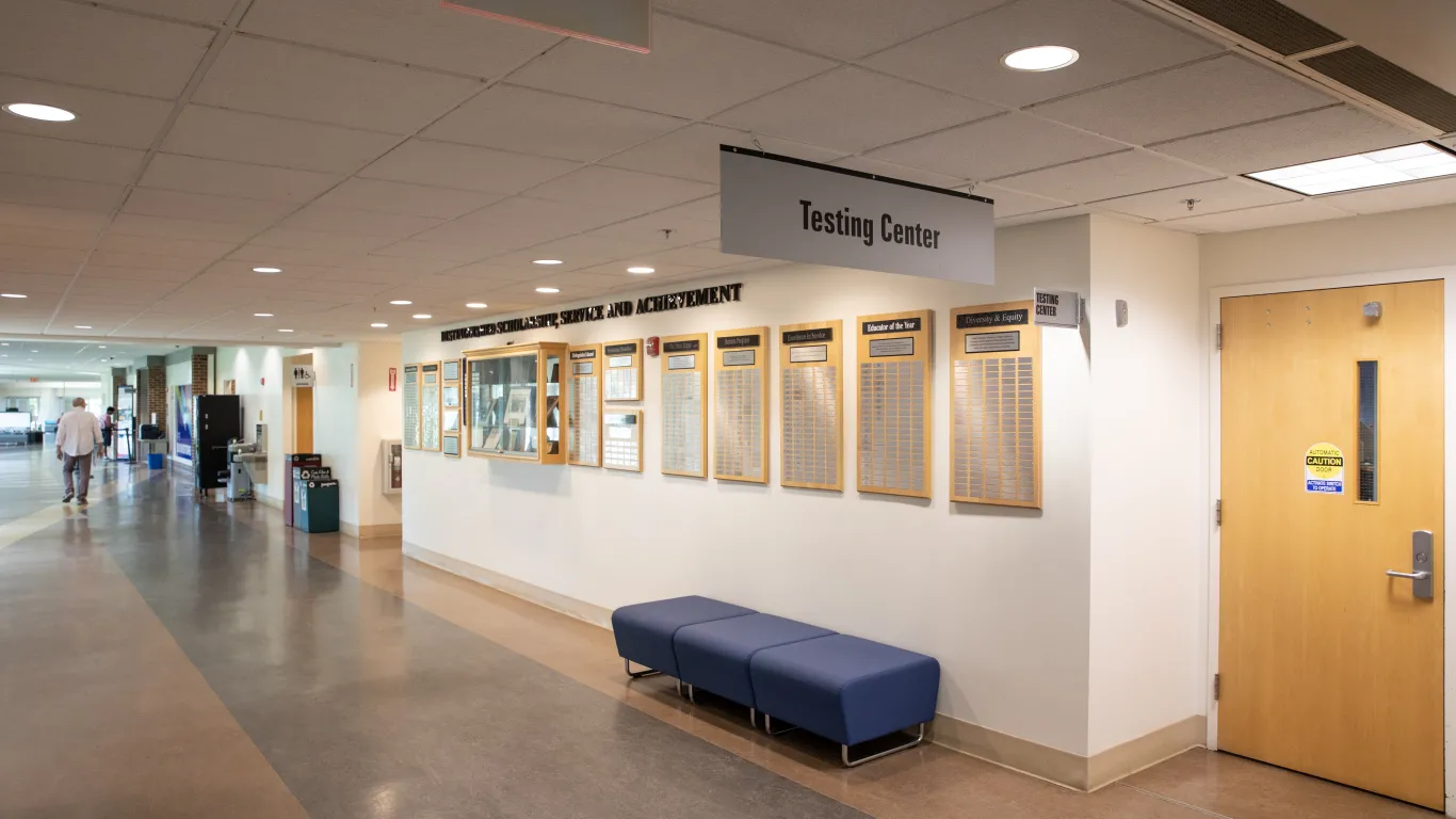 hallway with a bench and door with a sign over that reads testing center
