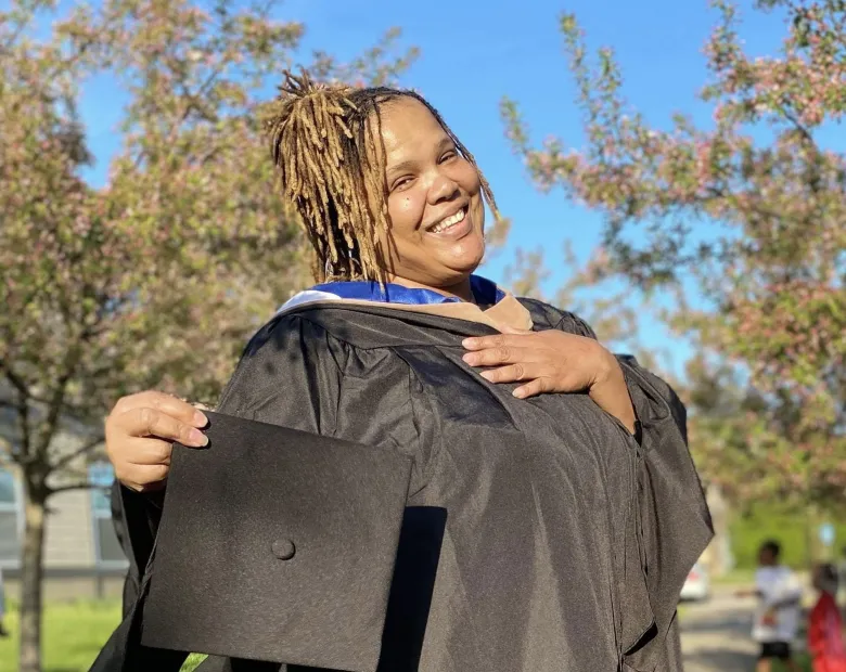 woman smiling outside with a cap and gown