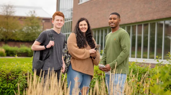 Three students outside a building on NHCC's campus in the fall