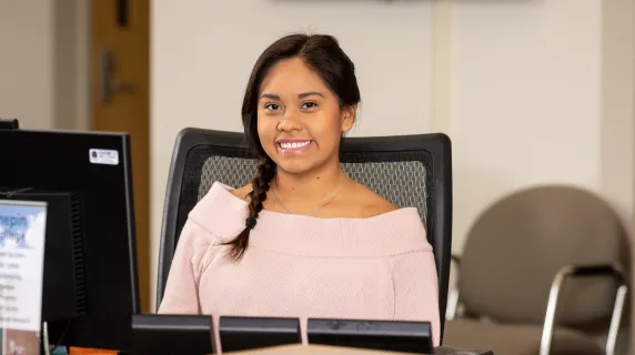 female student sitting at computer smiling