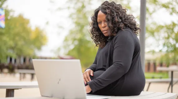 woman student working on her laptop outside