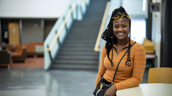 student smiling by stairs and windows