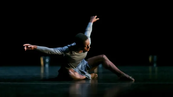 A solo dancer sitting on a stage