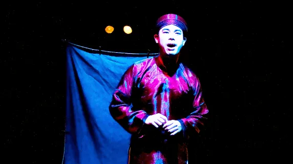An actor performing on a stage for the play "Reincarnation Soup"