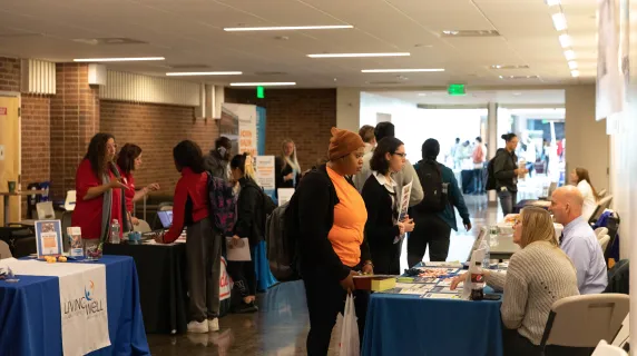 students talking with employers at tables in a hallway