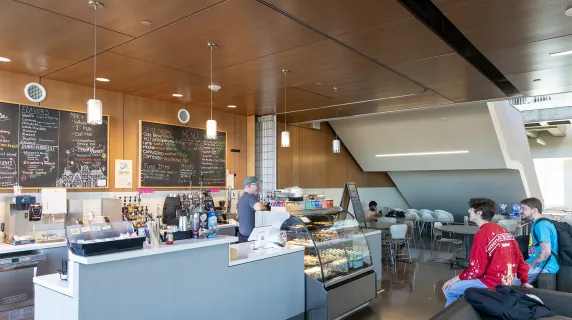 coffee shop with pastries behind glass and two students waiting