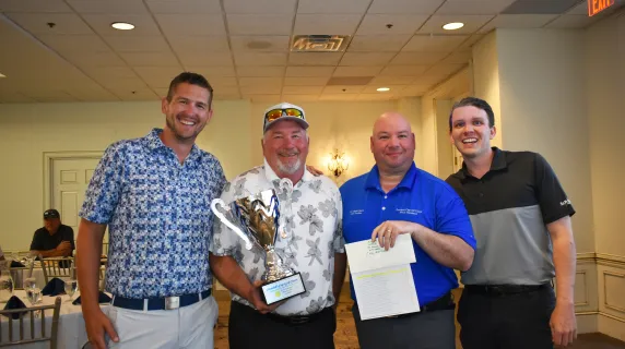 Three members of the winning golf team with NHCC President Garcia and the large silver President's Cup trophy