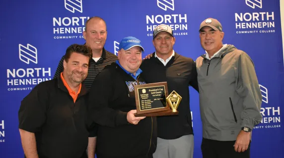 President Rolando Garcia with Team Osseo, the winners of the 2025 President's Cup Golf Classic City Trophy, holding the trophy for a photo