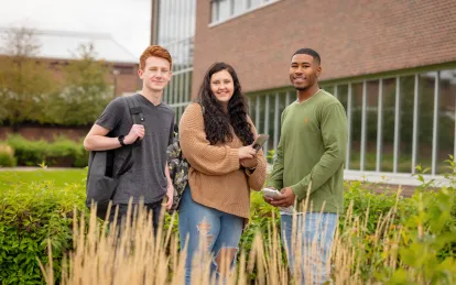 Three students outside a building on NHCC's campus in the fall