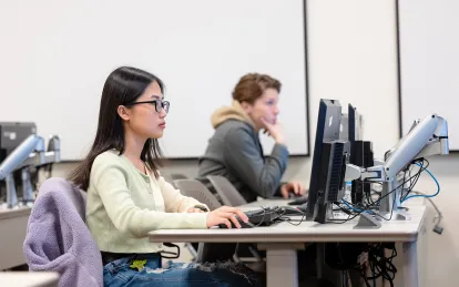 two students at computers in a classroom 