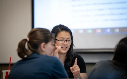 two students talking in a classroom 